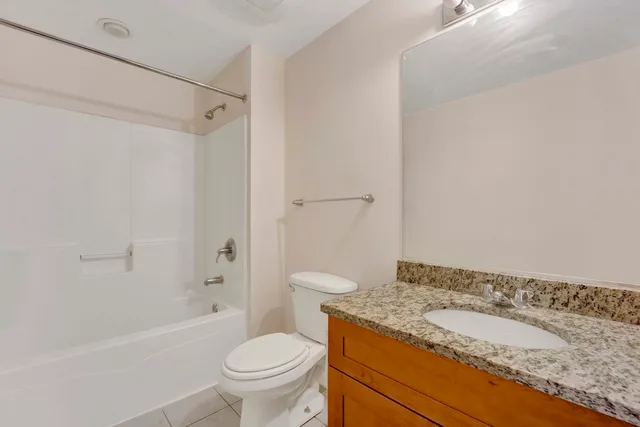a bathroom with a granite countertop sink a toilet and a bathtub