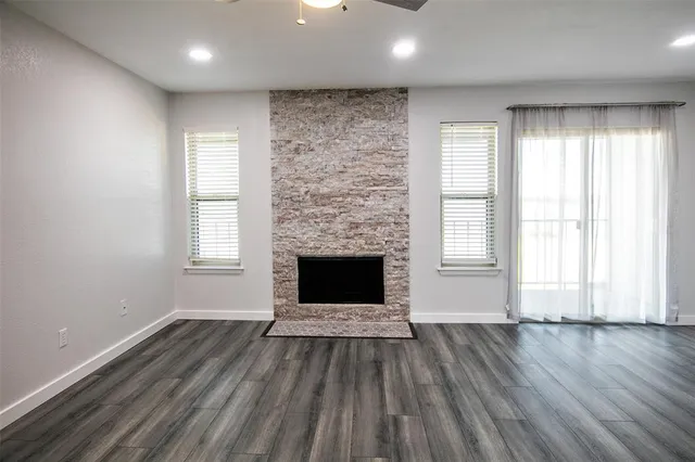 an empty room with windows a fireplace and wooden floor
