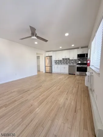a open kitchen with kitchen island a stove top oven a sink dishwasher and a fireplace with wooden floor