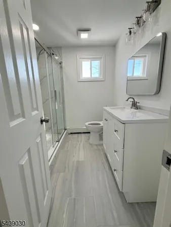 a spacious bathroom with a double vanity sink a toilet a mirror and shower
