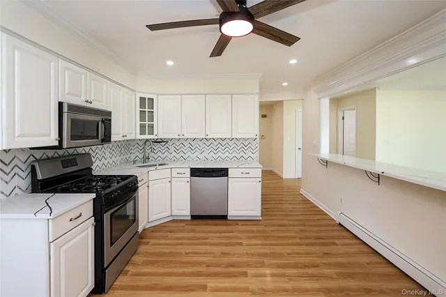 a kitchen with kitchen island granite countertop a stove top oven a sink a counter space and cabinets