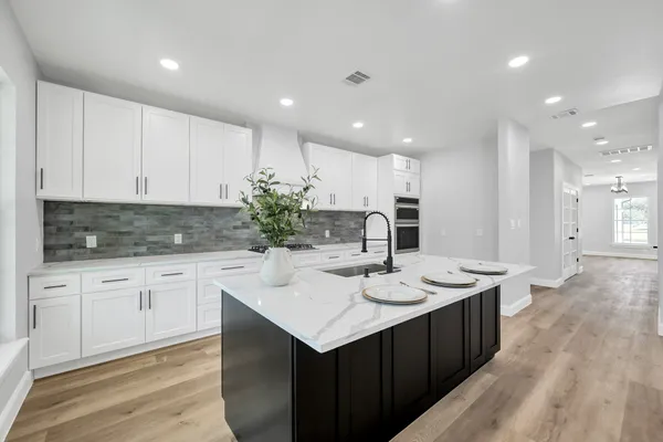 a kitchen with a sink white cabinets and wooden floor