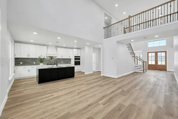 a large white kitchen with kitchen island a sink dishwasher a stove and a refrigerator with wooden floor