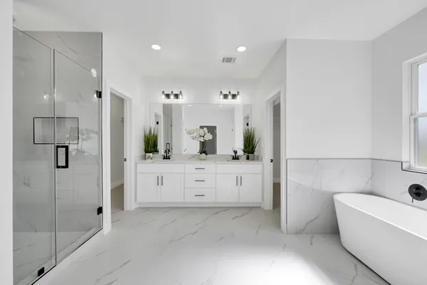 a bathroom with a bathtub a double vanity sink and mirror