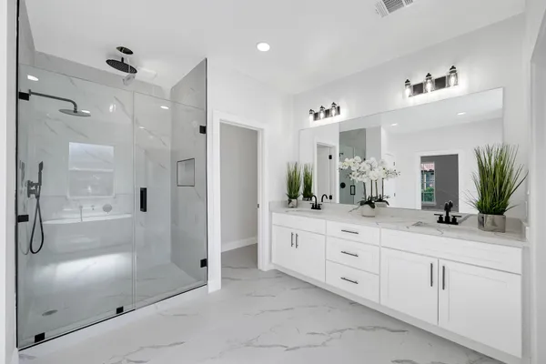 a bathroom with a double vanity sink mirror and shower