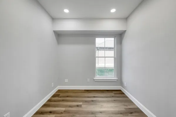 an empty room with wooden floor and windows