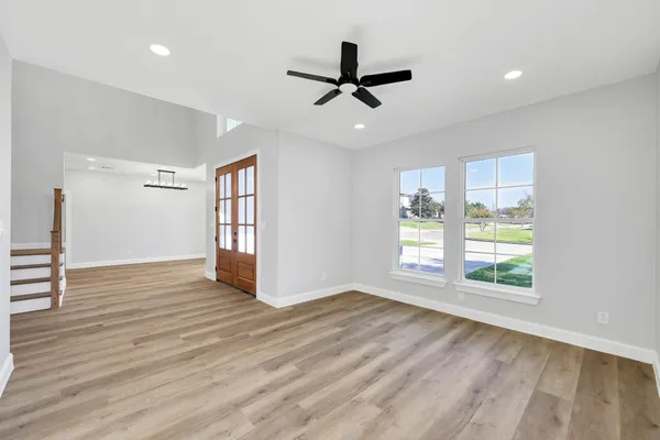 a view of an empty room with wooden floor and a window
