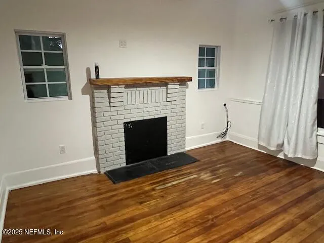 a view of empty room with wooden floor and fireplace
