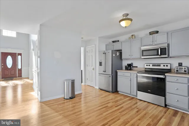 a kitchen with stainless steel appliances granite countertop a stove a sink dishwasher and a refrigerator with wooden floor