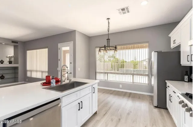 a kitchen with stainless steel appliances granite countertop a stove a sink a refrigerator and a wooden floor