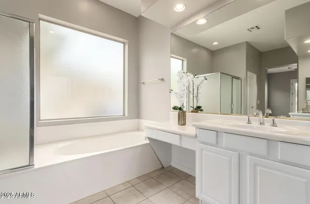 a bathroom with a bathtub a double vanity sink and mirror