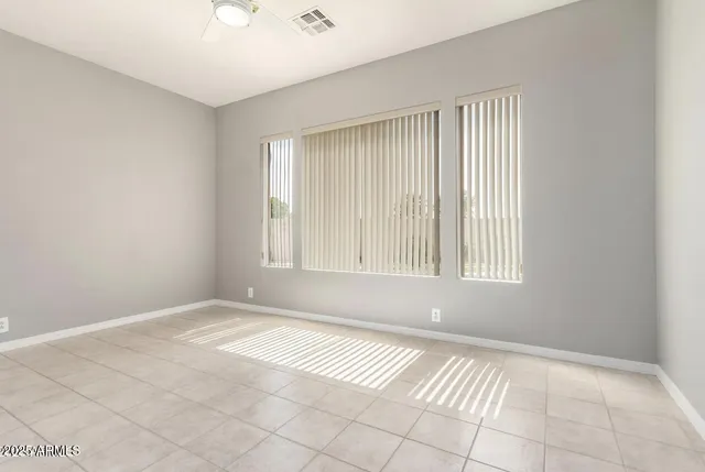 a view of an empty room with window and chandelier fan