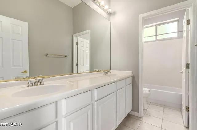 a white bath tub sitting next to a white toilet and vanity