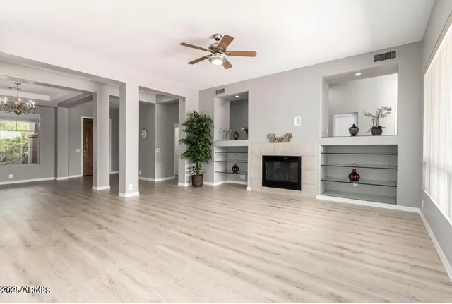 a view of a livingroom with a fireplace a chandelier and wooden floor