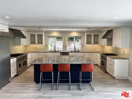 a kitchen with stainless steel appliances kitchen island a table chairs in it and wooden floors