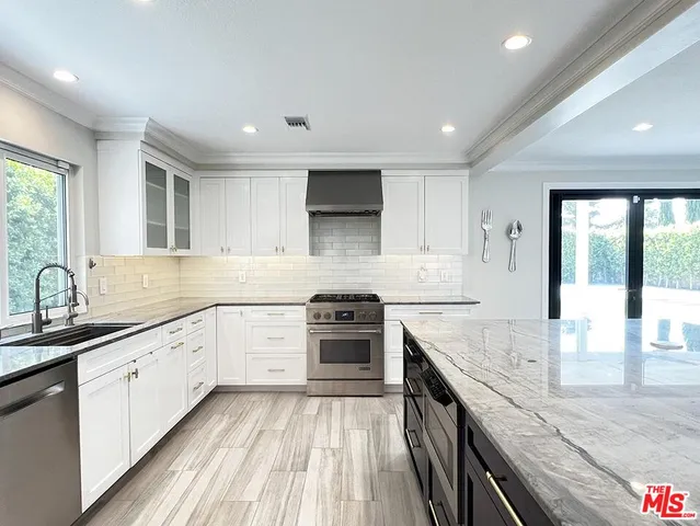 a large kitchen with stainless steel appliances granite countertop a lot of counter space and wooden floors