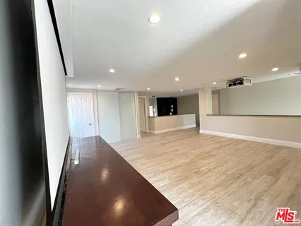 a view of an empty room with wooden floor and a ceiling fan