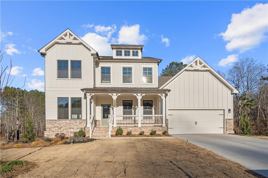 a view of a white house with large windows and a yard with plants