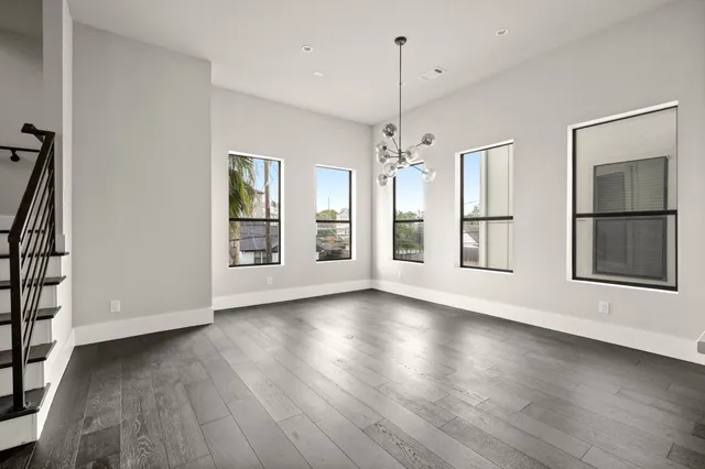 a view of an empty room with wooden floor fridge and a window