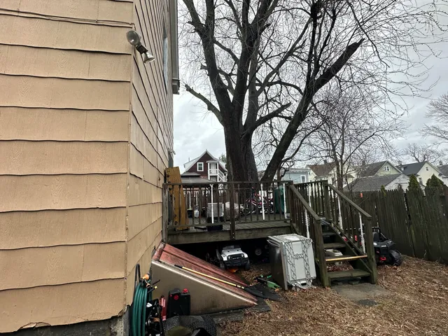 a view of backyard with wooden fence and a large tree