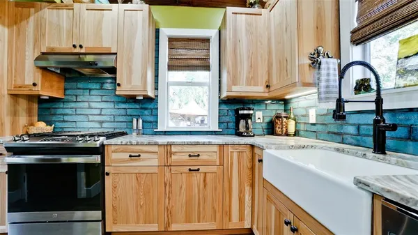 a kitchen with granite countertop a stove a sink and a microwave