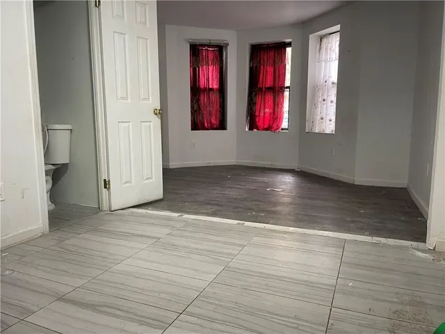 a view of an empty room with wooden floor and windows