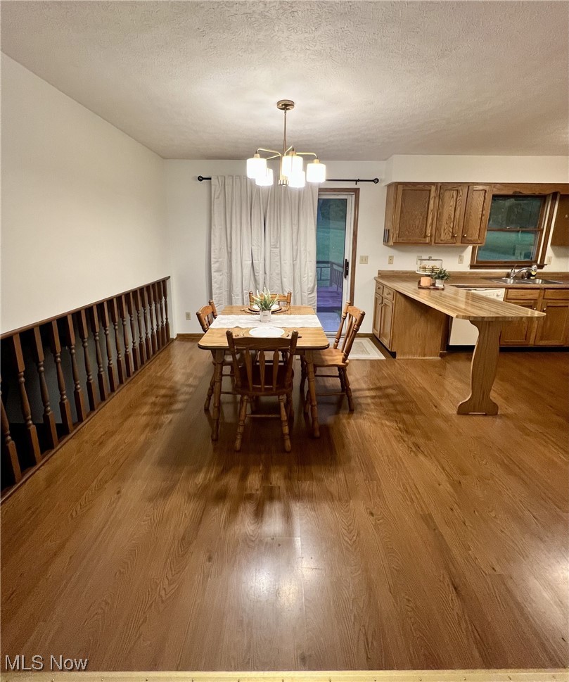 6443 Bloomfield Road Cambridge, OH 43725 - Photo 8 of 30 Dining room featuring hardwood / wood-style flooring, sink, a notable chandelier, and a textured ceiling