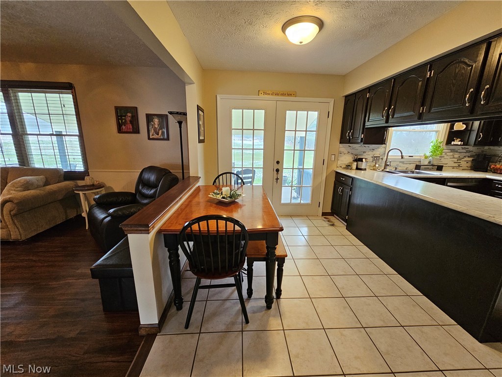 5100 Pierce Road Northwest Warren, OH 44481 - Photo 17 of 26 Kitchen with tasteful backsplash, french doors, sink, a textured ceiling, and light hardwood / wood-style flooring