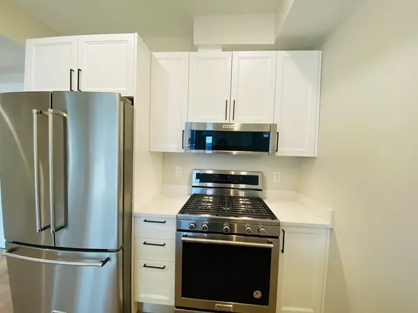 a kitchen with stainless steel appliances a refrigerator a stove and white cabinets