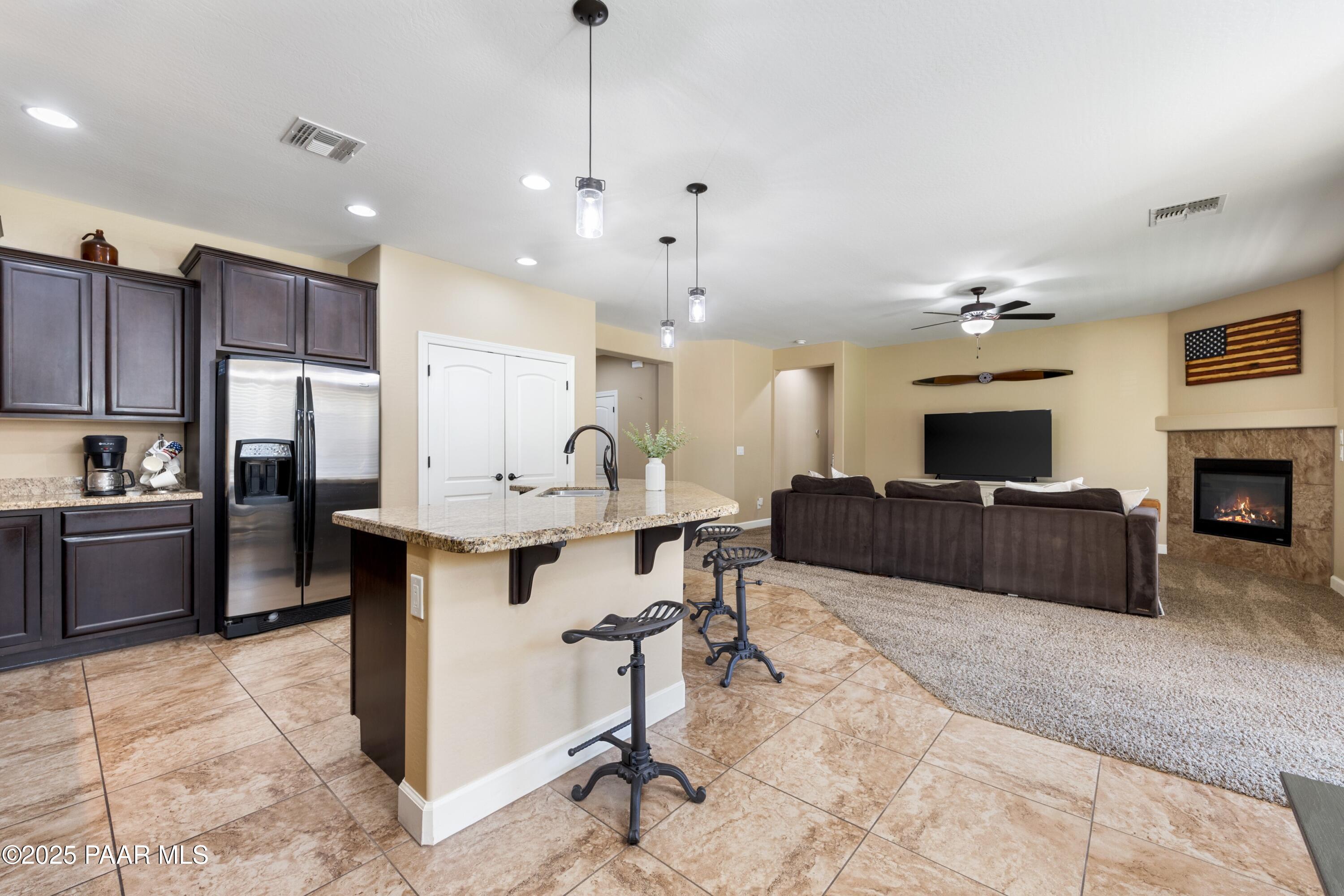 1200 Rusty Nail Road Prescott Valley, AZ 86314 - Photo 6 of 32 a large living room with stainless steel appliances kitchen island granite countertop couches a fireplace a flat screen tv and a kitchen island