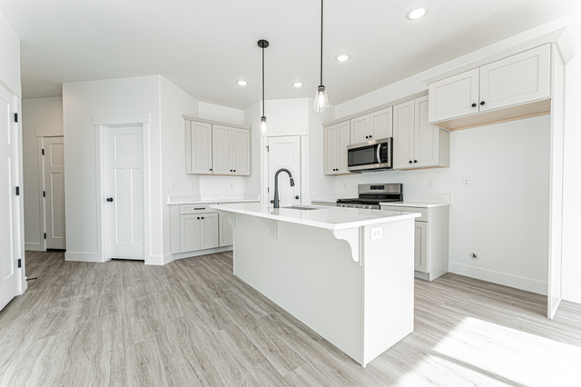 4774 Alder Drive Mapleton, UT 84664 - Photo 2 of 27 Kitchen featuring a breakfast bar, stainless steel appliances, light wood-style flooring, pendant lighting, and a center island with sink