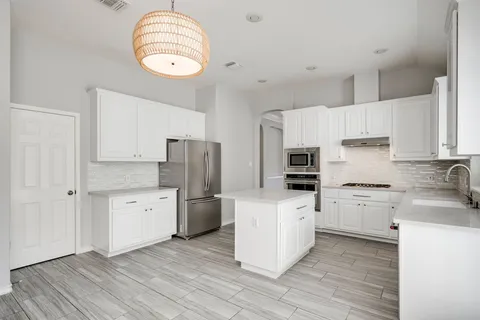 a kitchen with granite countertop white cabinets and stainless steel appliances