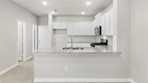 a kitchen with stainless steel appliances granite countertop a sink a refrigerator and a granite counter tops