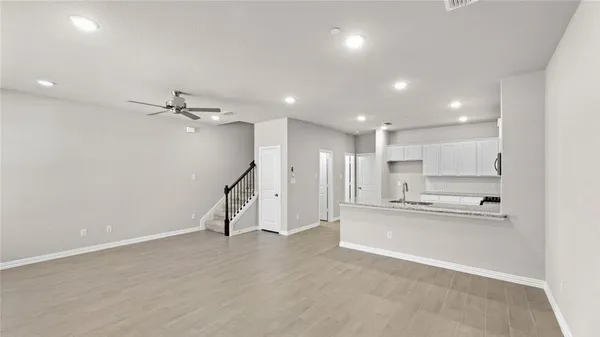 an empty room with wooden floor and a kitchen