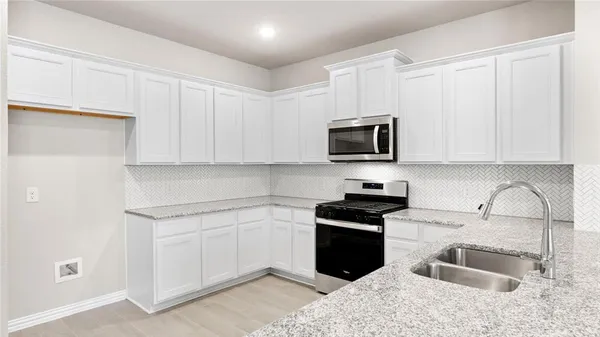 a kitchen with granite countertop white cabinets sink and stainless steel appliances