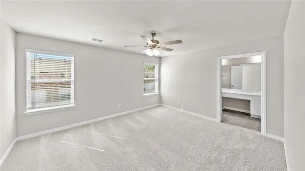an empty room with chandelier fan and windows