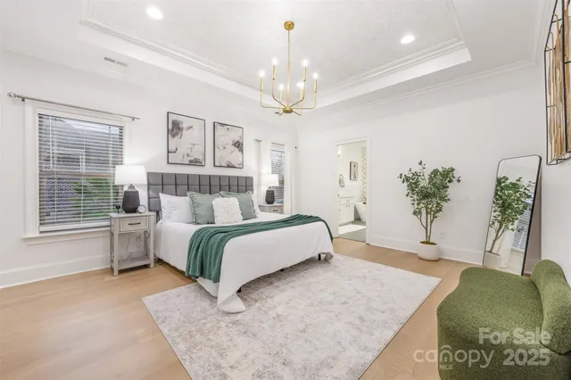 a spacious bedroom with a large bed chandelier and a window