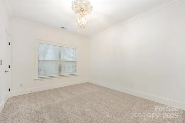 an empty room with a chandelier fan and windows