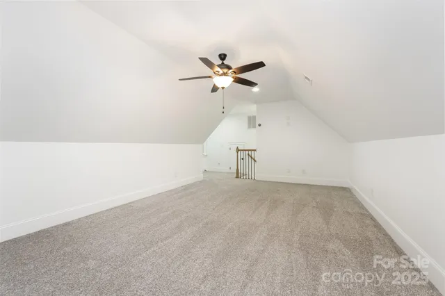 an empty room with a chandelier fan and windows
