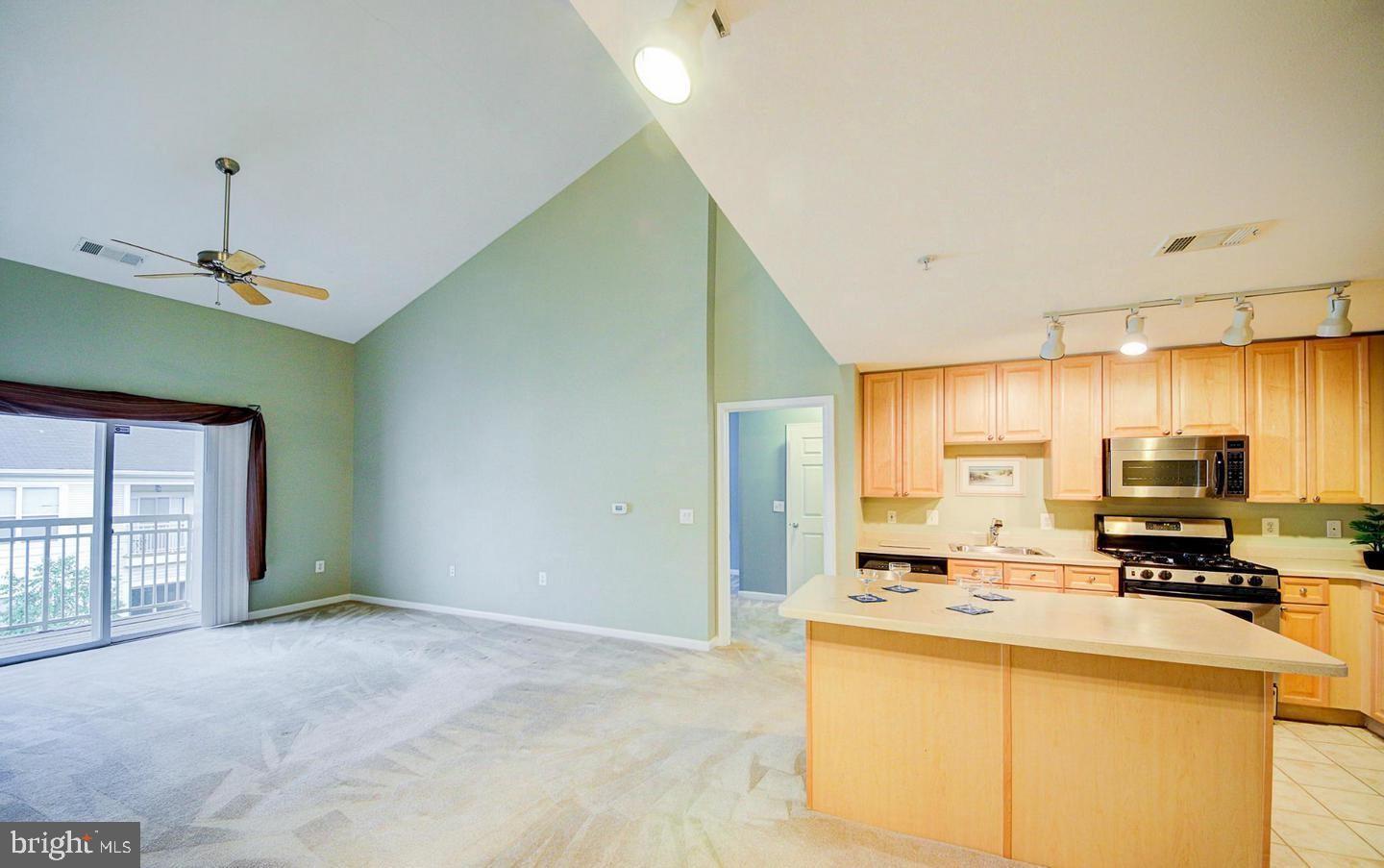 9480 Virginia Center Boulevard, Unit 420 Vienna, VA 22181 - Photo 8 of 17 a kitchen with stainless steel appliances a stove top oven a sink a refrigerator white cabinets and couches with wooden floor