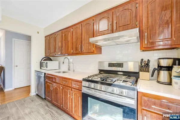 a kitchen with stainless steel appliances granite countertop a stove a sink and a microwave