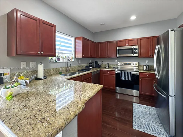 a kitchen with stainless steel appliances granite countertop a sink stove refrigerator and microwave