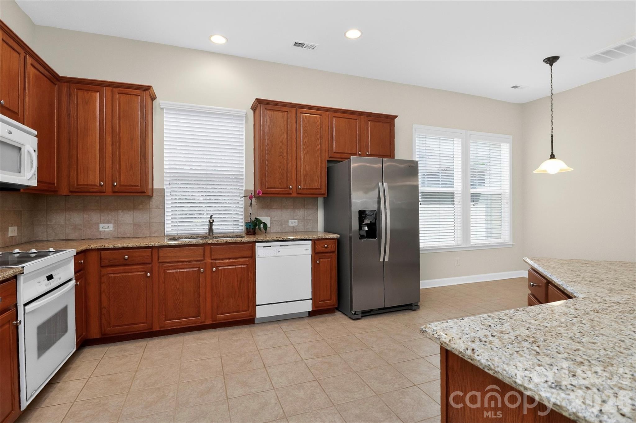 9315 Rosalyn Glen Road Cornelius, NC 28031 - Photo 13 of 35 a kitchen with stainless steel appliances granite countertop a refrigerator a stove and sink