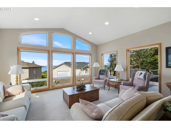 a living room with furniture large windows and wooden floor
