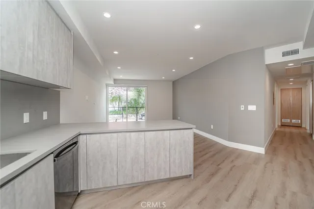 a living room with stainless steel appliances wooden floors and white walls