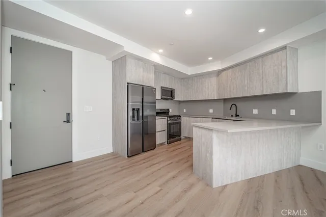 a kitchen with stainless steel appliances granite countertop a refrigerator a sink a stove and a wooden floors