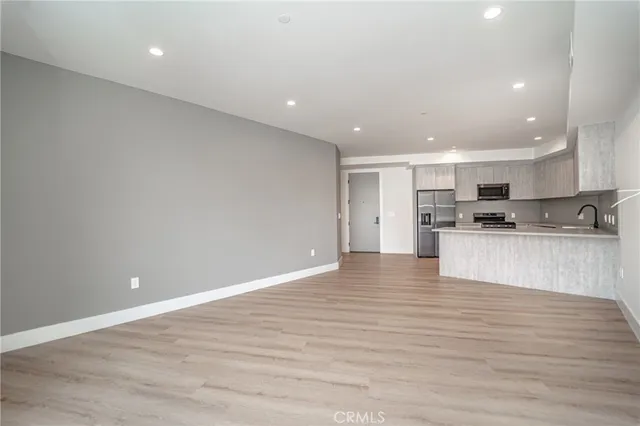 a view of kitchen with kitchen island a sink wooden floor and a refrigerator
