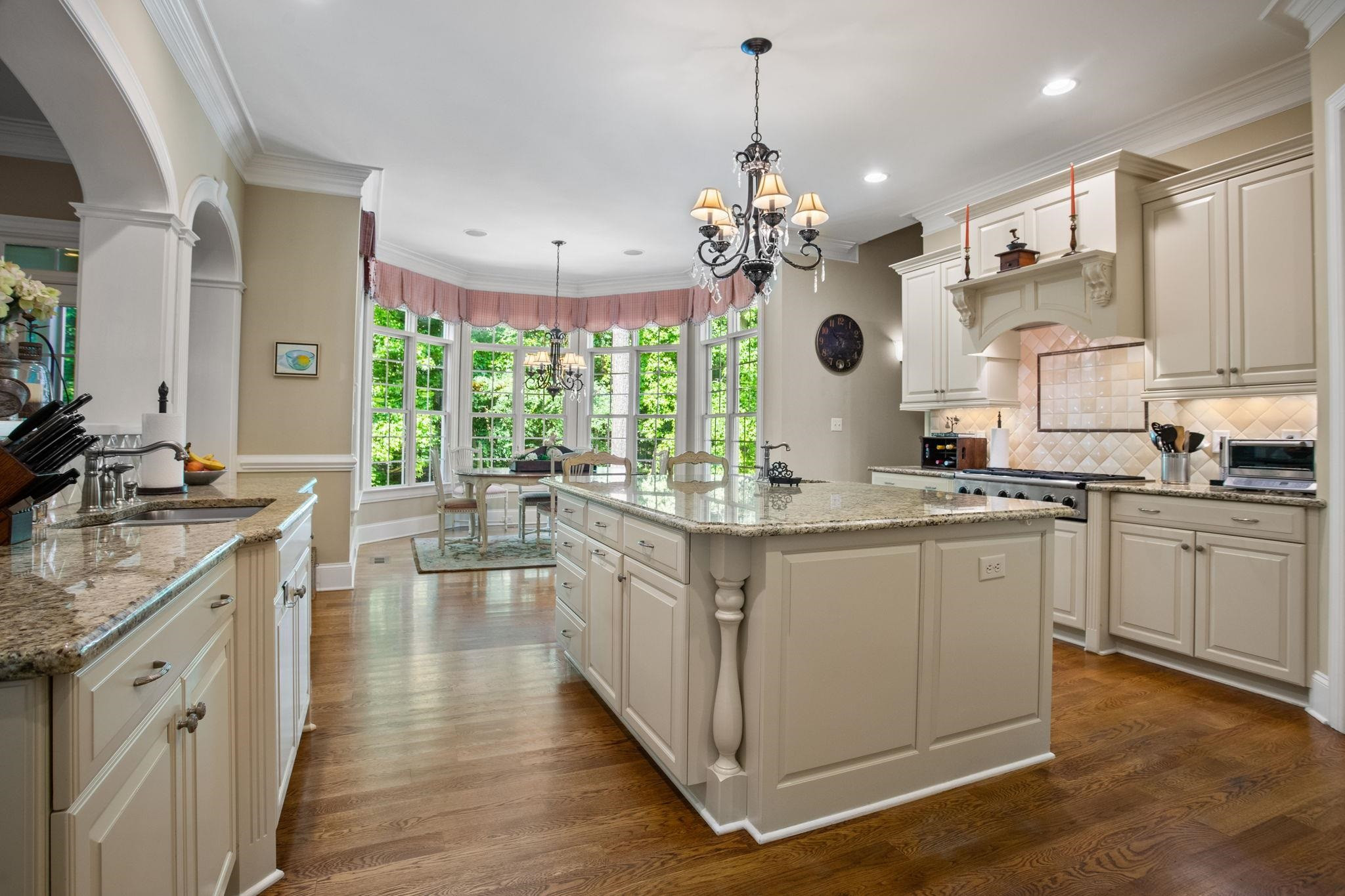 3223 Rain Forrest Way Raleigh, NC 27614 - Photo 18 of 71 a large kitchen with granite countertop a large stove a sink dishwasher and white cabinets with wooden floor