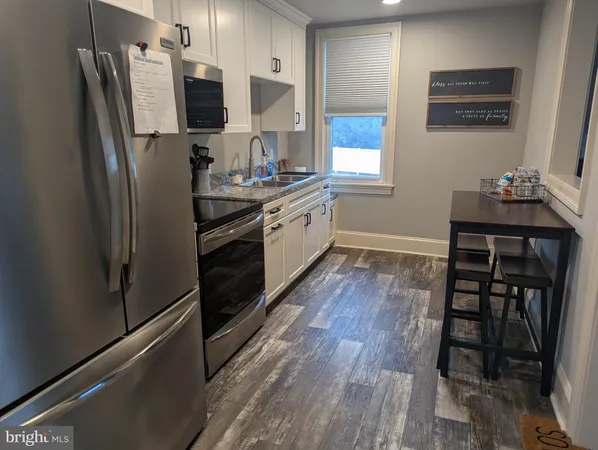 a kitchen with stainless steel appliances a refrigerator sink and wooden floor