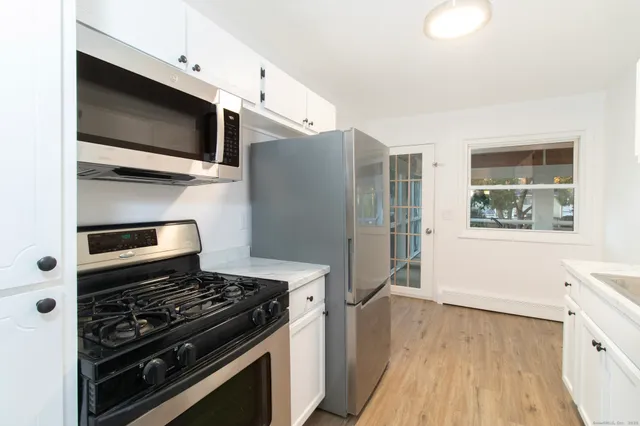 a kitchen with stainless steel appliances a stove a microwave and a hard wood floor